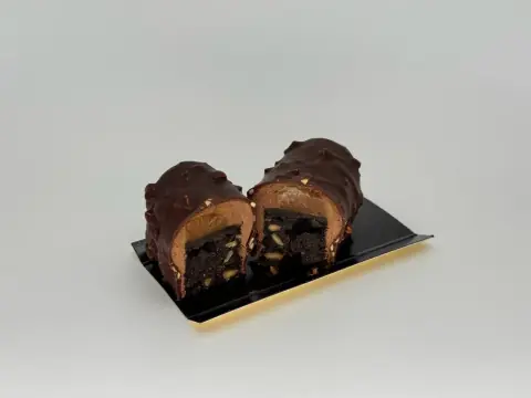 Brownie–chocolate mousse dessert - Peanut brownie layered with silky caramel, wrapped in airy chocolate mousse, and finished with a dark chocolate glaze studded with crunchy nuts.