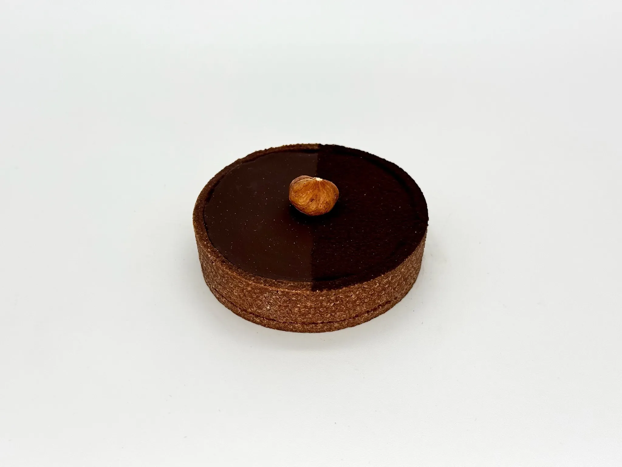 Crunchy Dark Chocolate Tartlet - Pure chocolate indulgence. Chocolate crunchy sable crust layered with a delicate crunchy praline layer, velvety chocolate ganache, and finished with a glossy chocolate glaze and black cocoa finish. Intense, elegant, and irresistibly decadent.